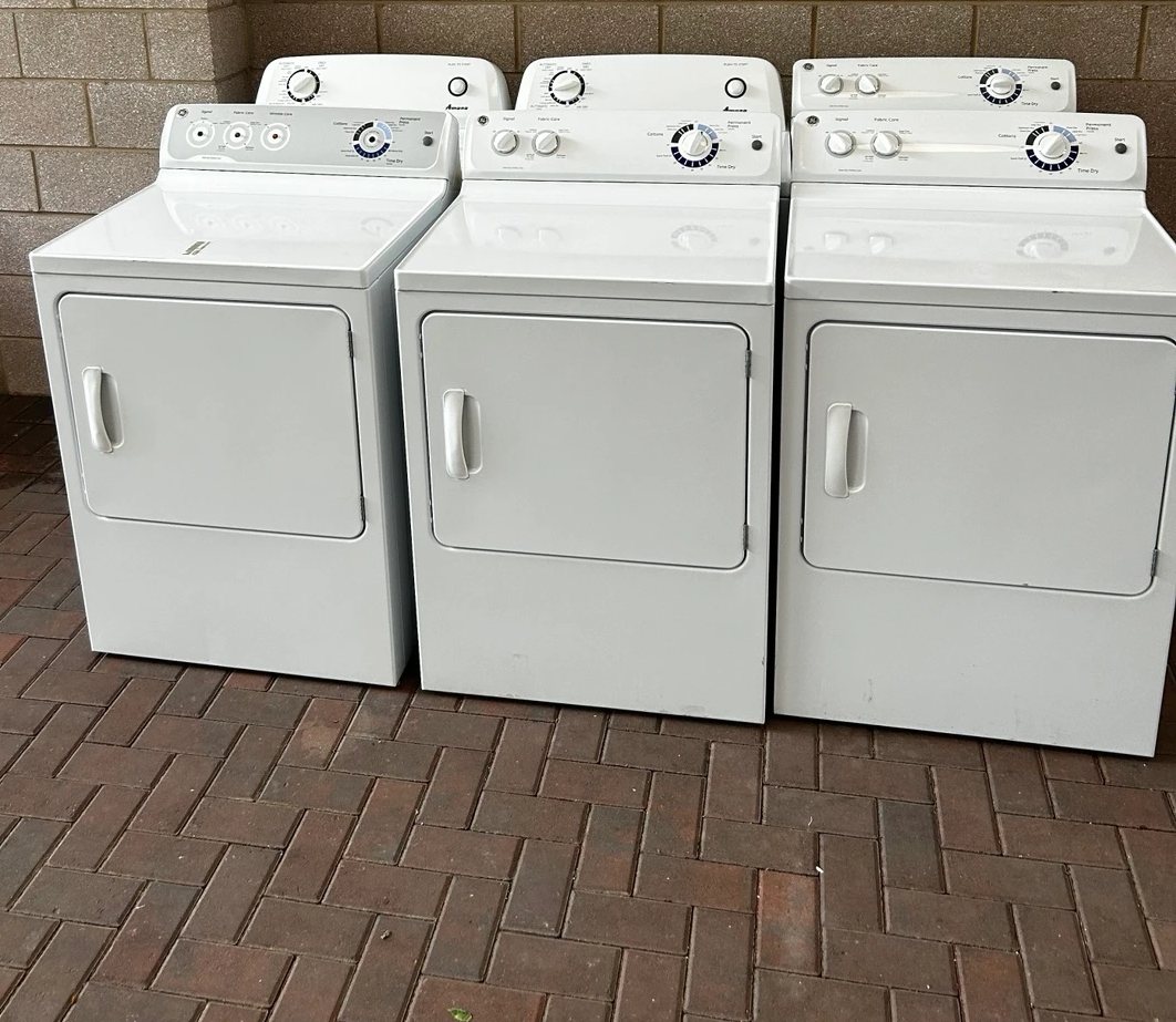 Three white electric dryers lined up